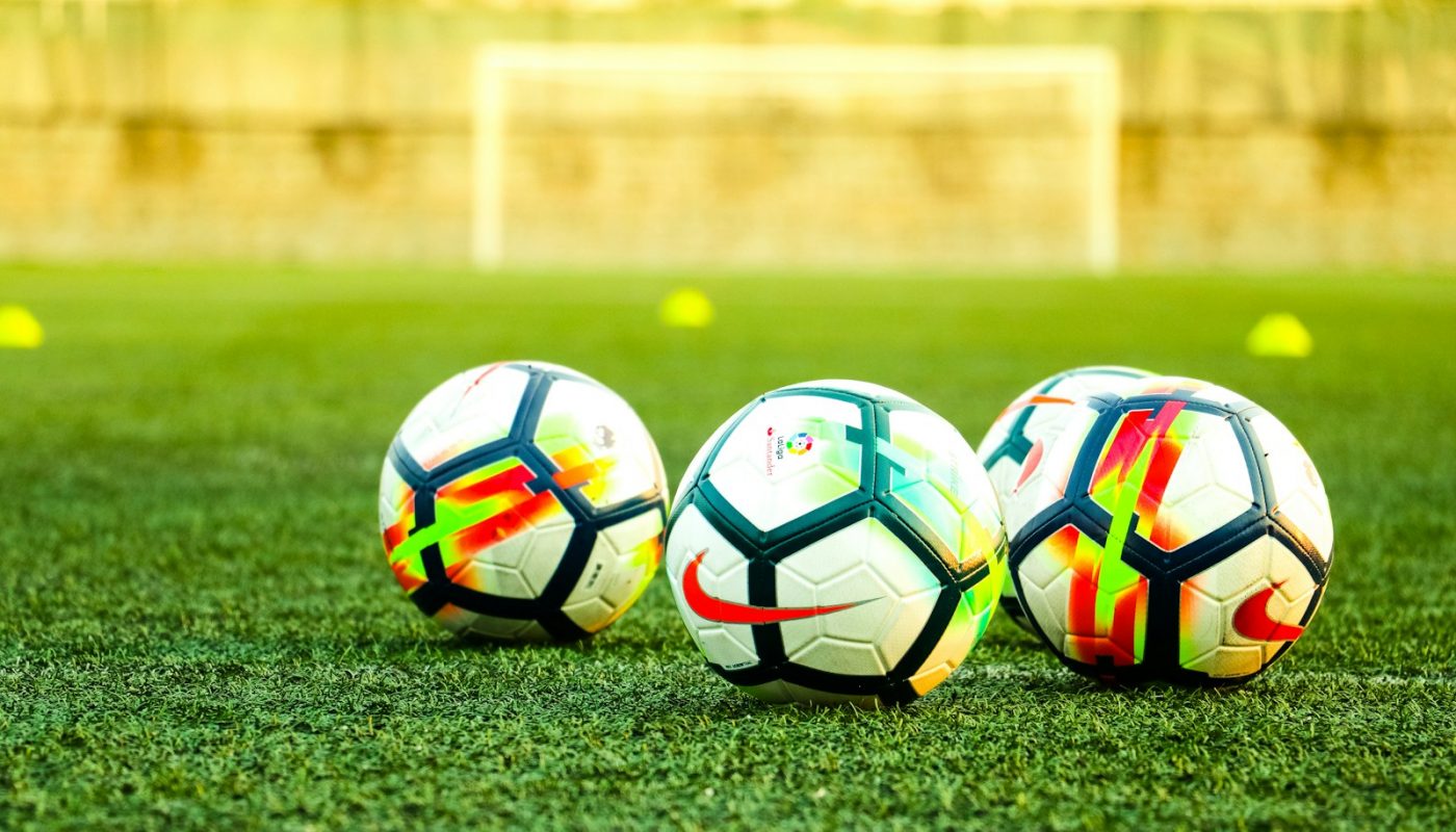 three white-and-black soccer balls on field